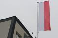 Flaga Polski na maszcie i fragment budynku