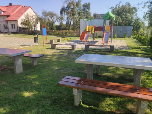 Plac zabaw: stoły do gier planszowych z ławkami, zjeżdżalnie na piaszczystym podłożu